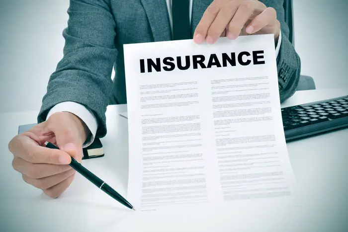 stock image of a man holding an insurance company form that says "Insurance " at the top